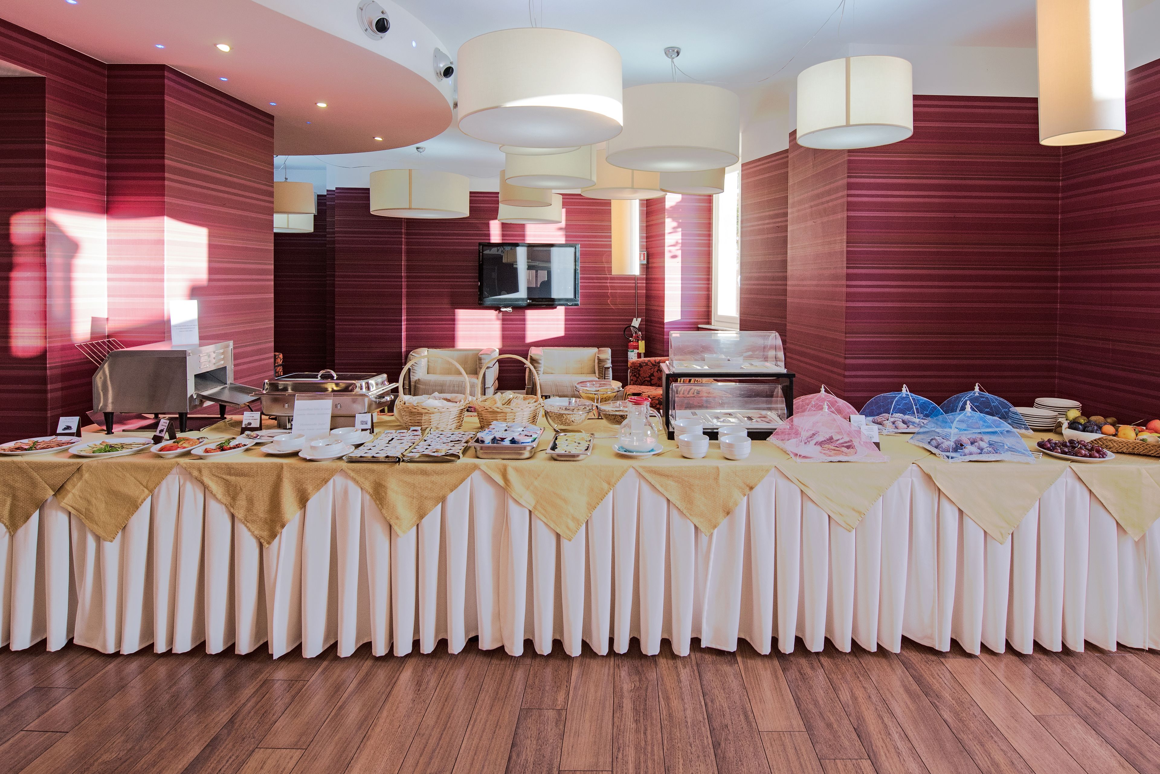 A buffet setup with various food items and a television in a room with red walls and wooden flooring.