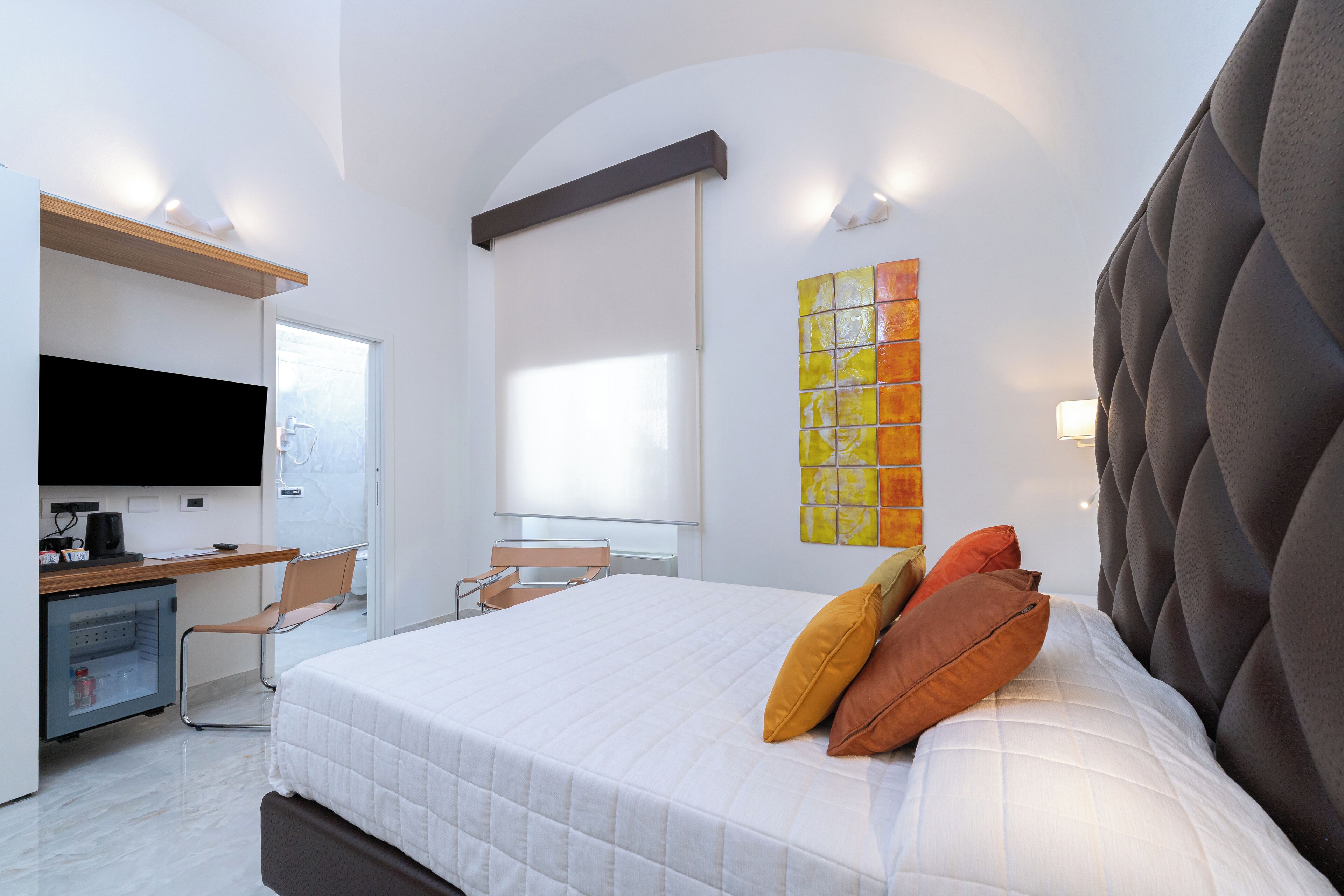 Een moderne hotelkamer met een groot bed, een bureau, een stoel, een televisie en een kunstwerk aan de muur.