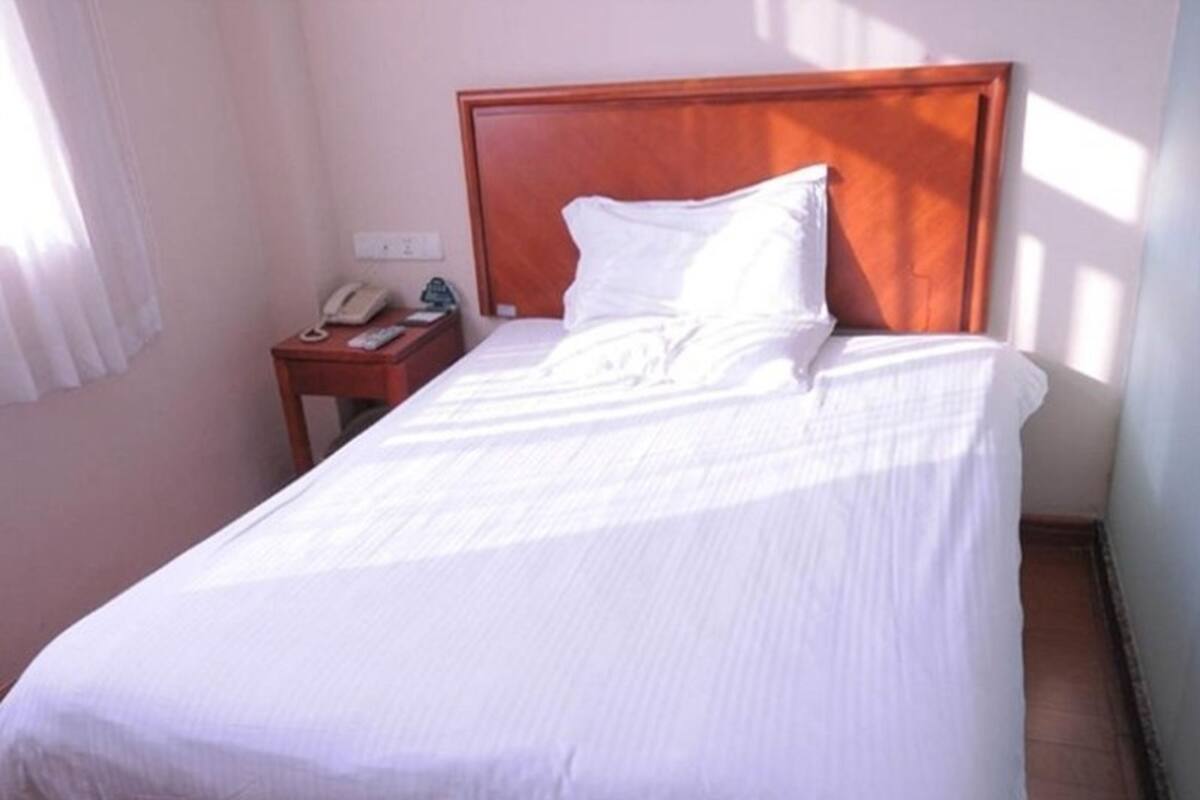 A neatly made bed with a wooden headboard in a hotel room.