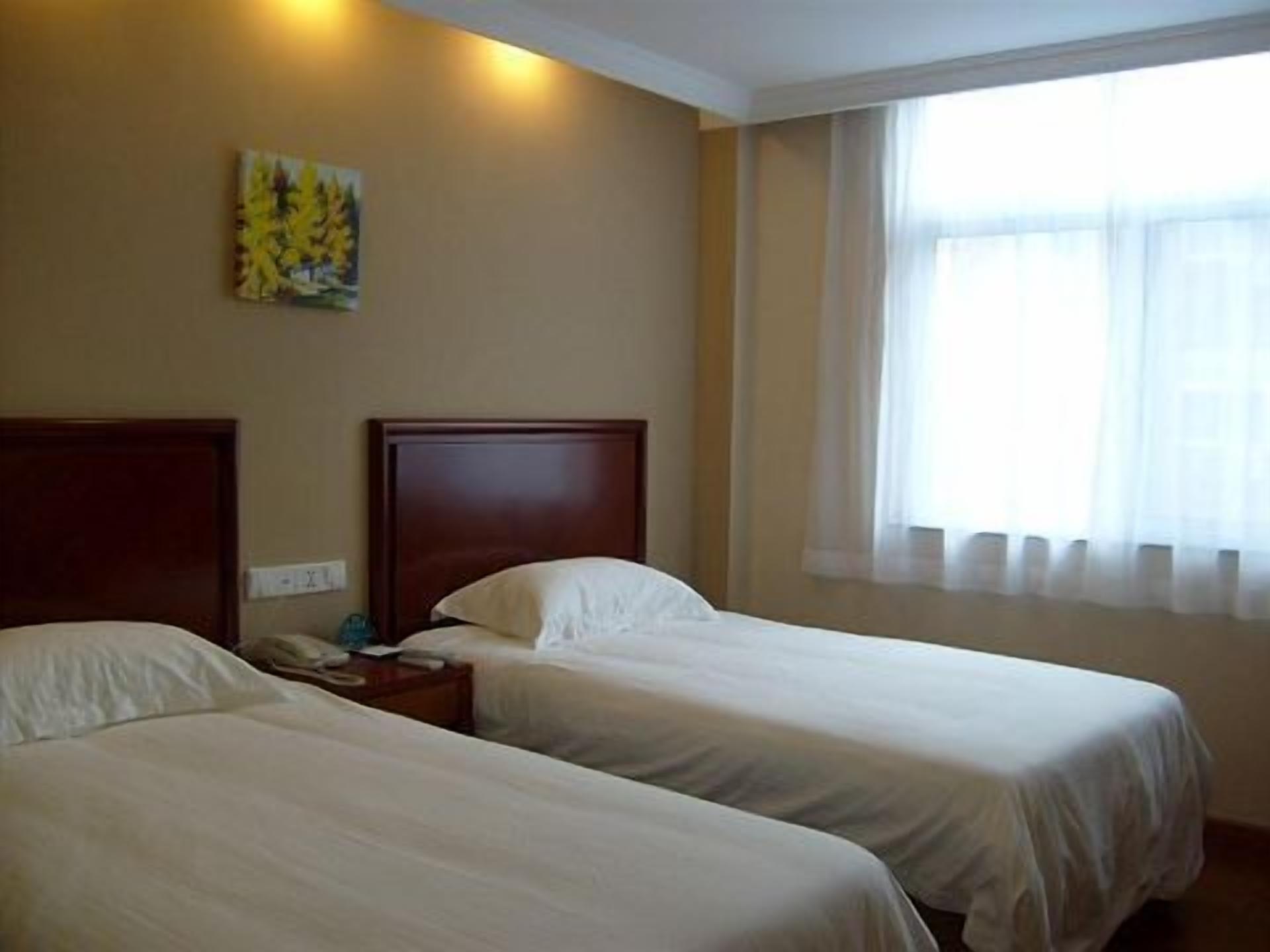 A hotel room with two beds, a nightstand, and a painting on the wall.