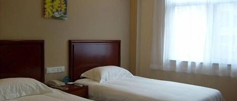 A hotel room with two beds, a nightstand, and a painting on the wall.