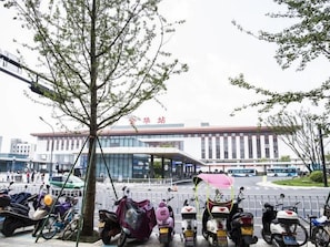 Un edificio moderno con fachada de vidrio, un árbol en primer plano y varias scooters estacionadas.