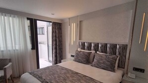 Quarto de hotel moderno com uma cama grande, uma escrivaninha e vista para o exterior.