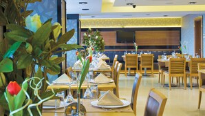 Um restaurante moderno com mesas compridas, cadeiras e plantas decorativas.