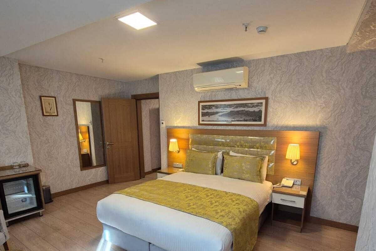 A hotel room with a large bed, bedside lamps, a desk with a chair, and a mirror.