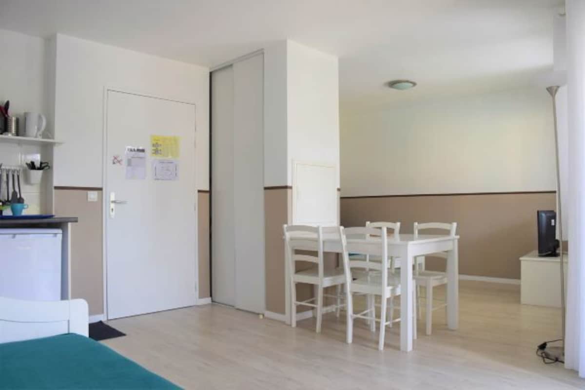 Una habitación con cama, escritorio, silla, mesa y puerta.
