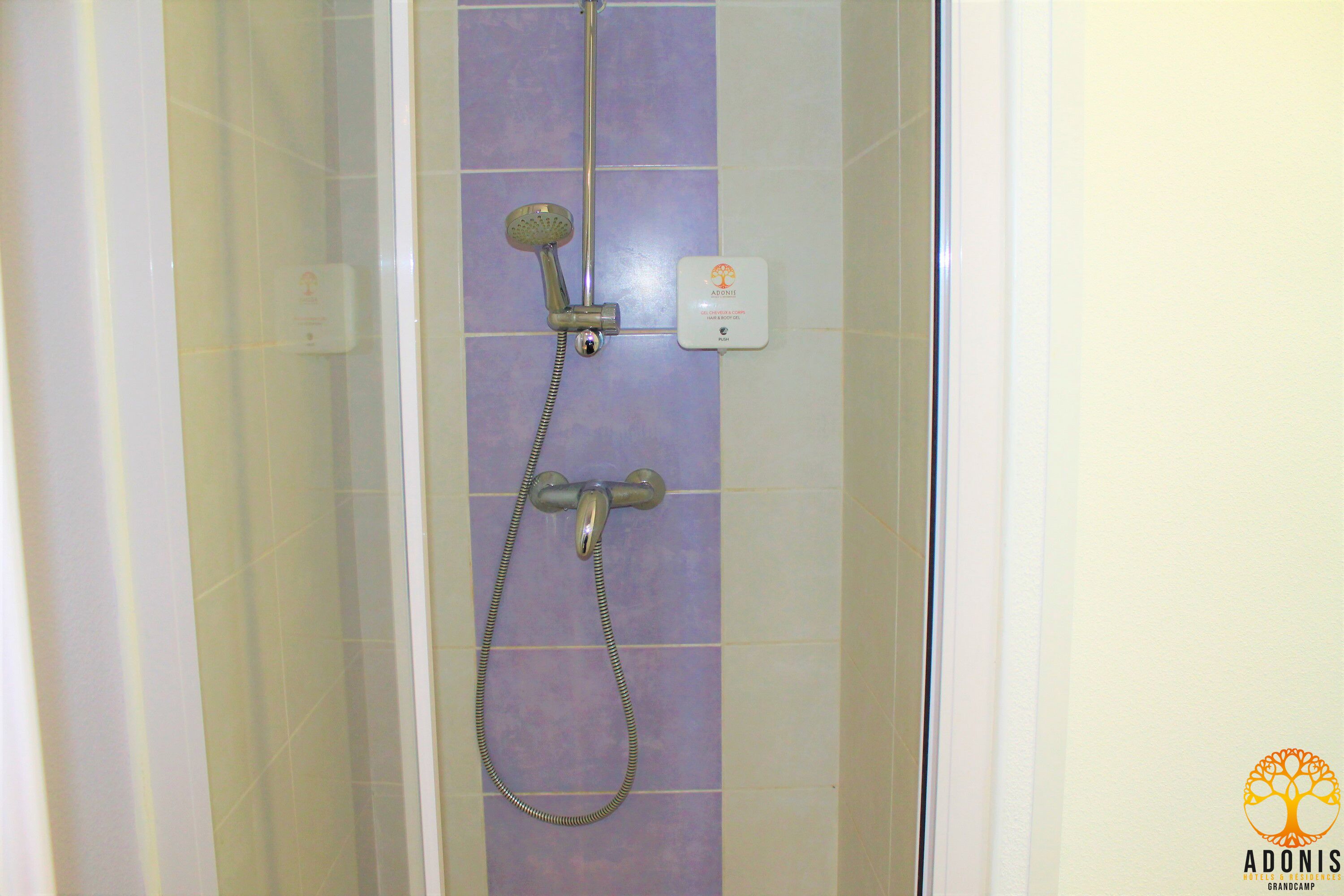 Een douche met een handdouche en een bedieningspaneel aan de muur.