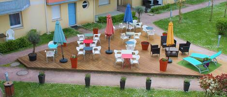 Un patio con mobiliario exterior, plantas en macetas y una pequeña zona de juegos.