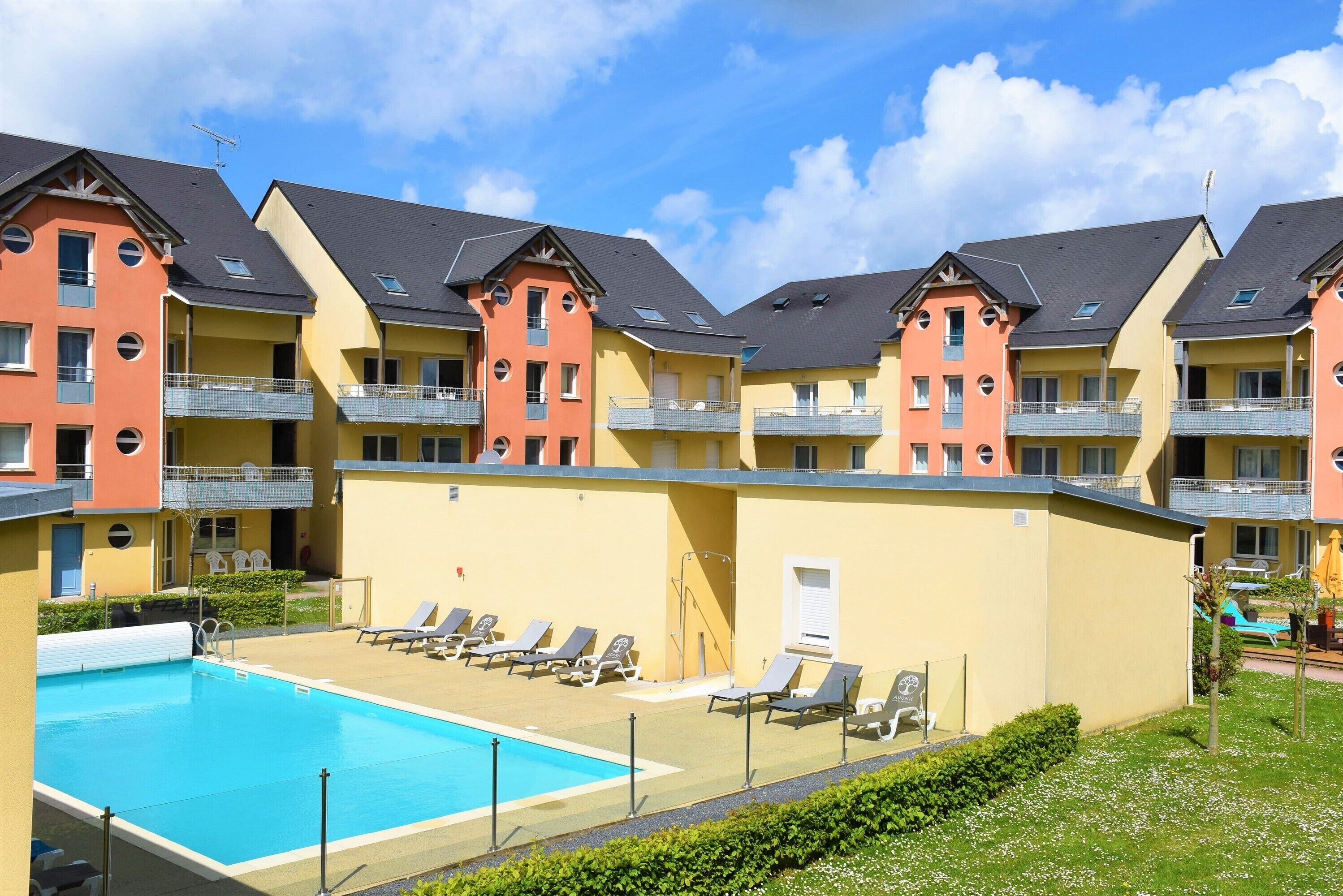 Un hotel de varios pisos con piscina y tumbonas.
