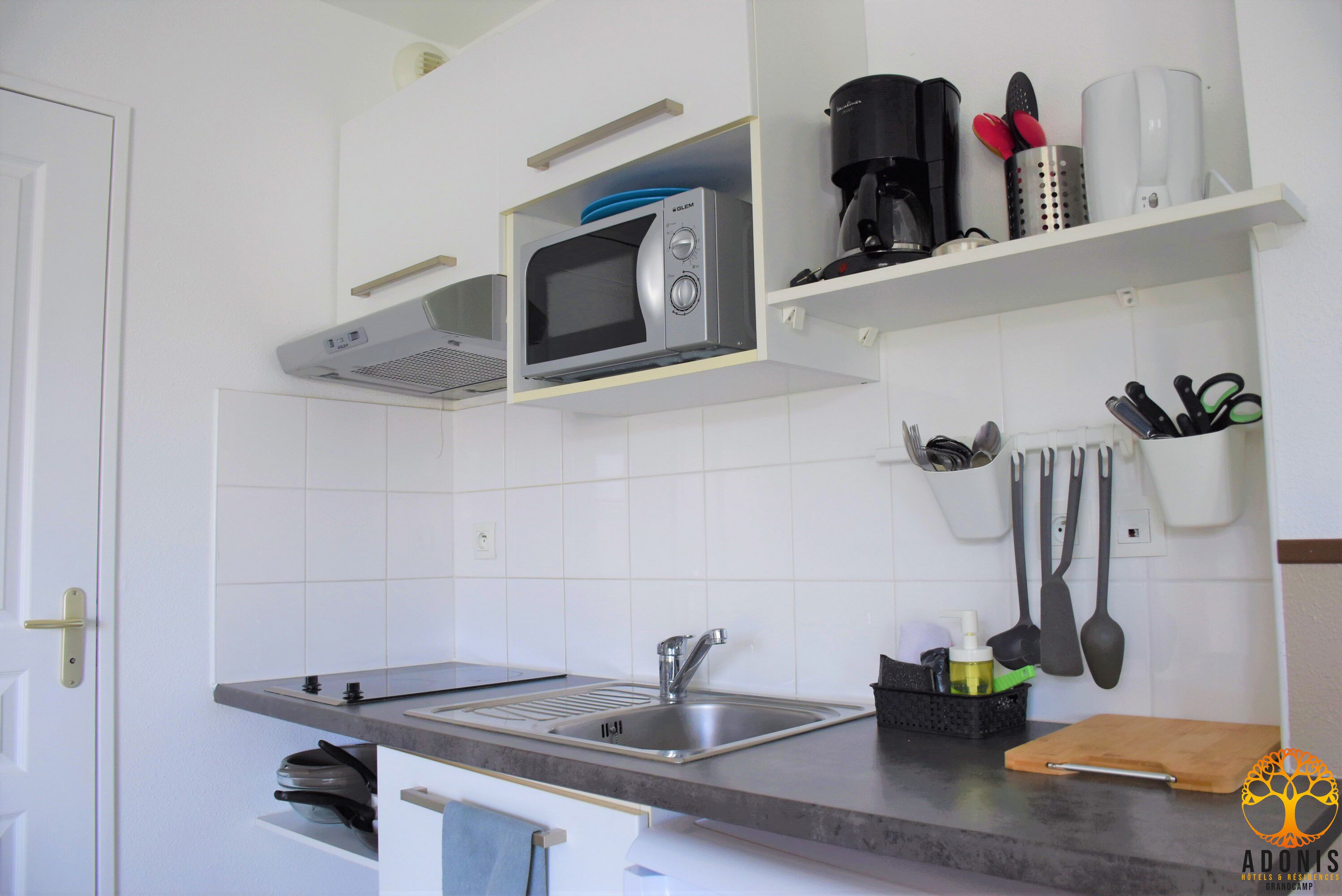 A kitchen with a built-in microwave, a coffee maker, and a knife block on the wall.