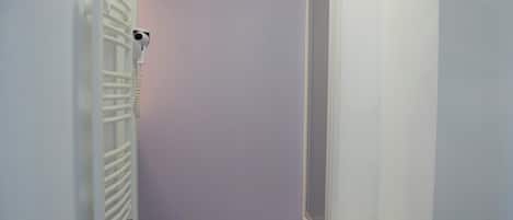 A narrow hallway with a radiator, a small white stool, and a door leading to another room.
