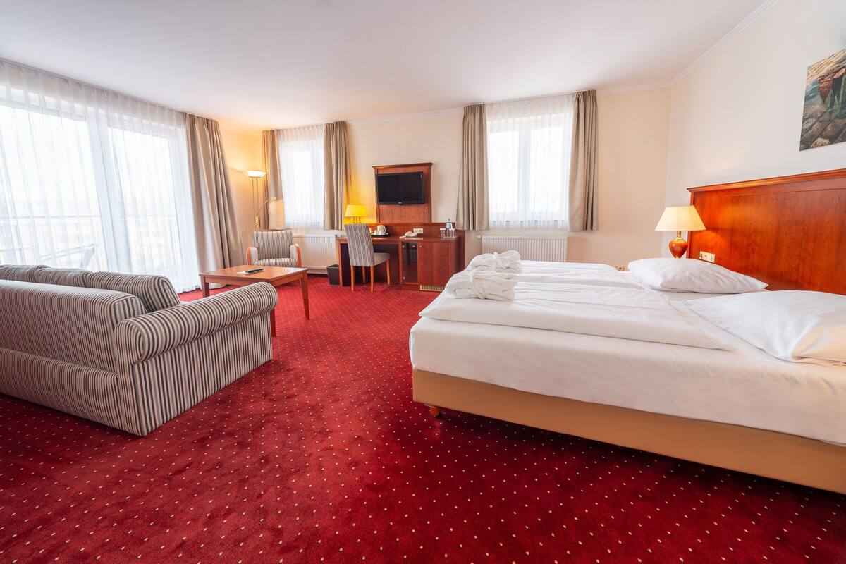Een hotelkamer met een groot bed, een bureau met stoel, een bank en een televisie.