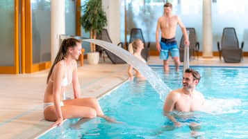 Ein Innenpool mit klarem Wasser, Liegestühlen und Fliesenboden.
