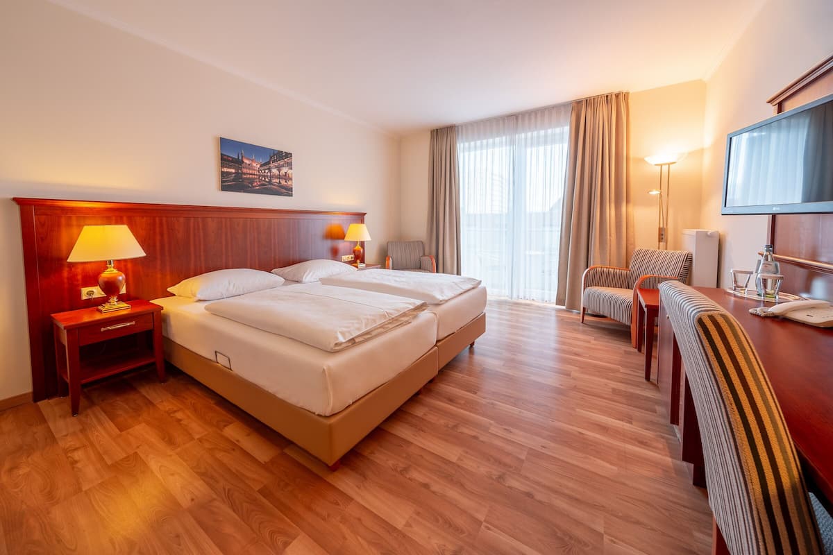 Een hotelkamer met een tweepersoonsbed, een bureau met stoel, een televisie en een lamp.