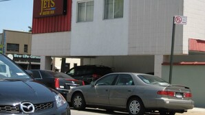 Un bâtiment avec une enseigne indiquant « Jets Motor Inn » et un panneau « Interdiction de stationner ». Des voitures sont garées devant.