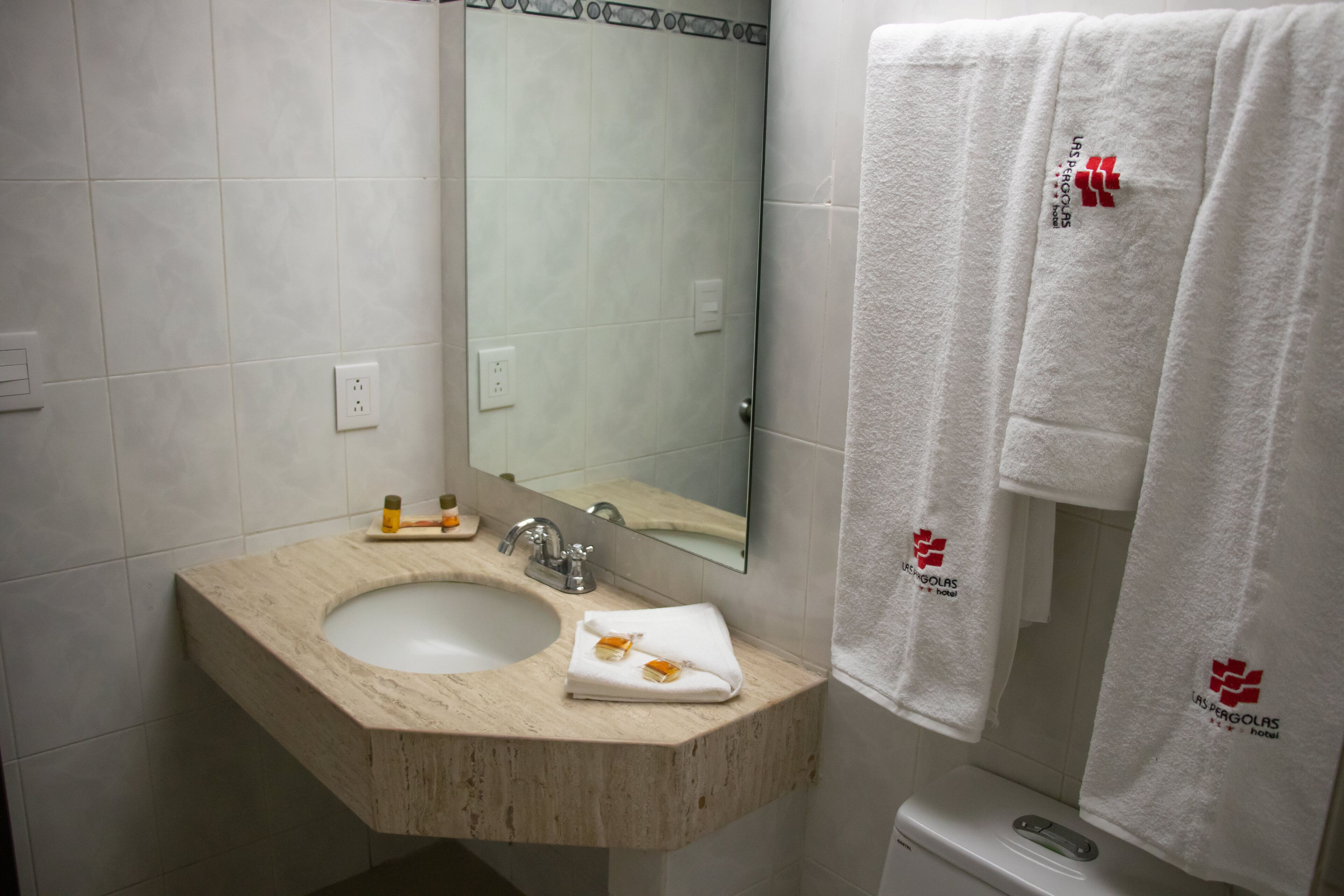 A bathroom with a beige sink, a mirror, and two white towels hanging on the wall.