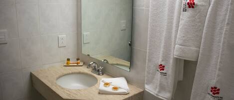 A bathroom with a beige sink, a mirror, and two white towels hanging on the wall.