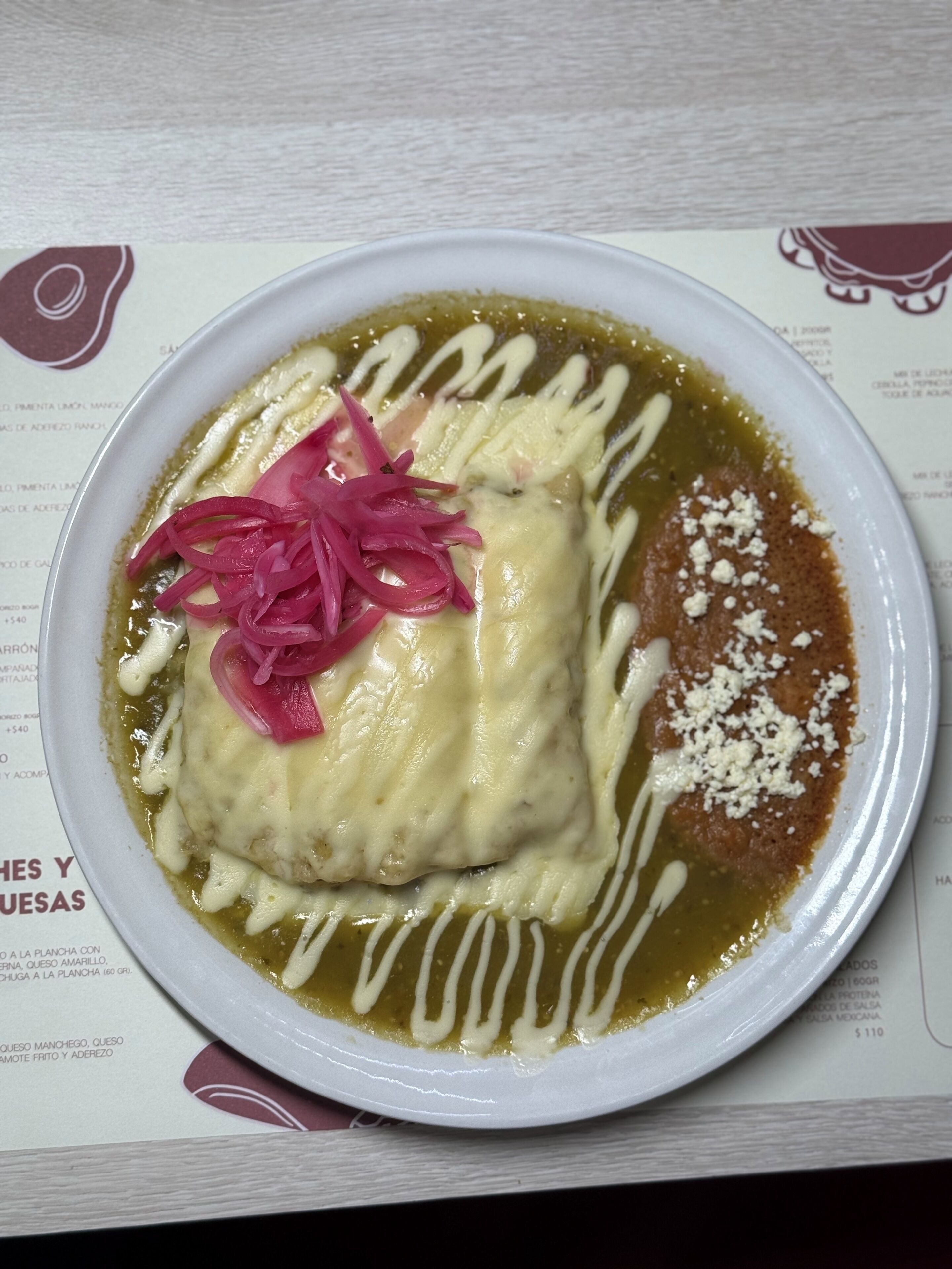 A plate of food with a creamy sauce, pickled onions, and a brown sauce, served on a white plate.