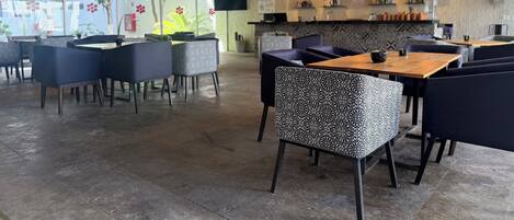 A modern restaurant interior with high ceilings, patterned chairs, and a bar area.