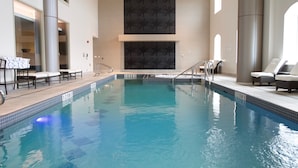 An indoor swimming pool with clear water, lounge chairs, and a modern design.