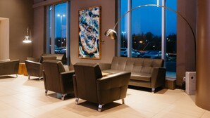 A modern lobby with a large window, a contemporary sofa, and a floor lamp.