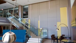 A modern lobby with a glass staircase, a blue seating area, and a hanging pendant light.