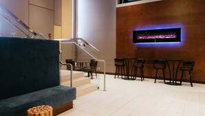 A modern lobby with a staircase, a blue sofa, a fireplace, and a seating area with chairs.