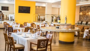 A restaurant with round tables, wooden chairs, and a central bar area. - Hotel Mirabel (Querétaro)
