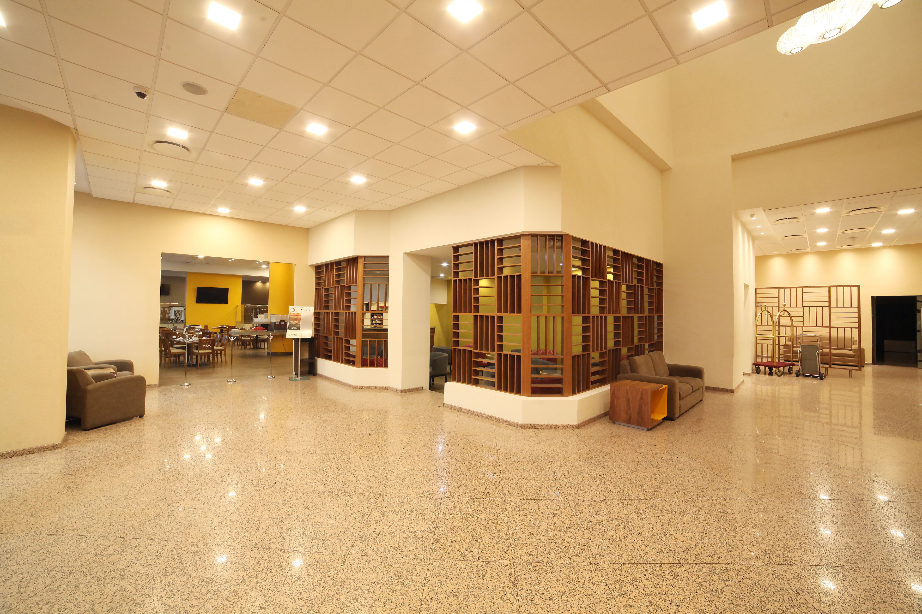 A spacious lobby with a polished floor, a seating area, and a reception desk.