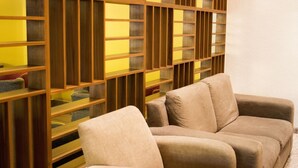 A room with a wooden bookshelf and two beige sofas. - Hotel Mirabel (Querétaro)