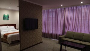 Hotellihuone, jossa on sänky, televisio, sohva ja sohvapöytä.