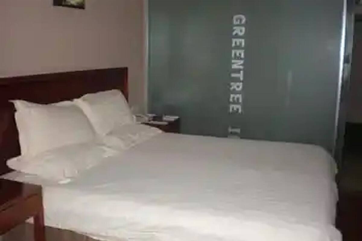 Un lit bien fait, avec du linge de lit blanc, dans une chambre d’hôtel.