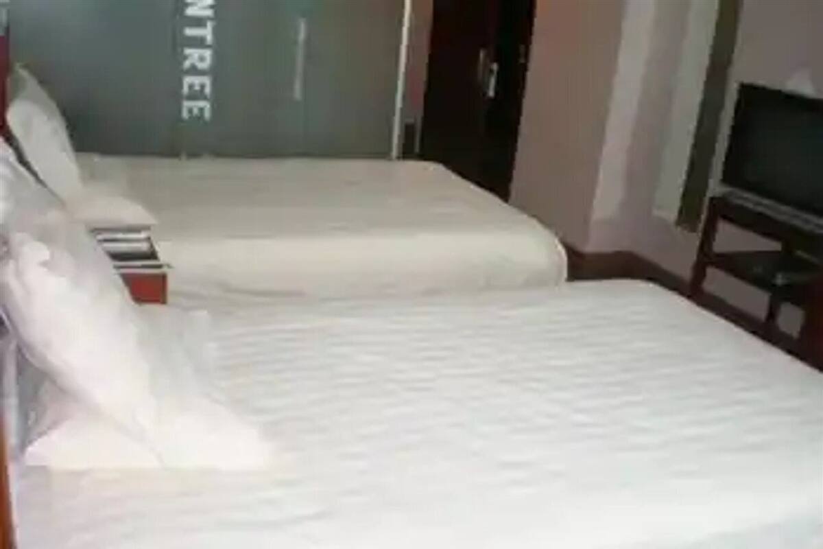 Une chambre d’hôtel avec deux lits, un téléviseur posé sur un meuble et une armoire.
