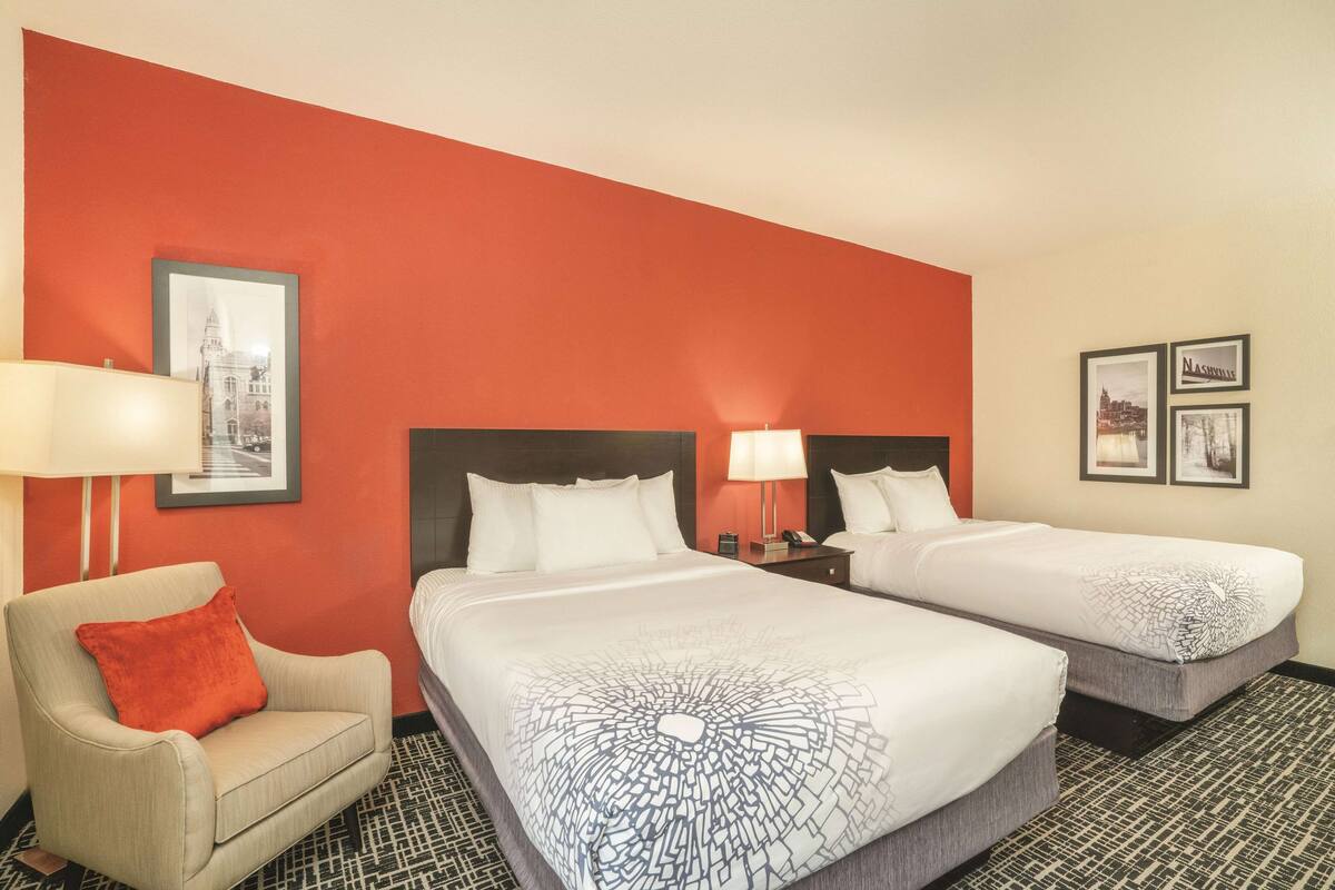 Ein Hotelzimmer mit zwei Betten, einer Couch und einer roten Akzentwand.