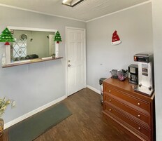 Una habitación de hotel con un aparador de madera, una cafetera, un cesto de basura pequeño y una puerta.