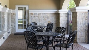 Eine Terrasse im Freien mit Steinmauern, einer weißen Tür und einem runden Tisch mit Stühlen.