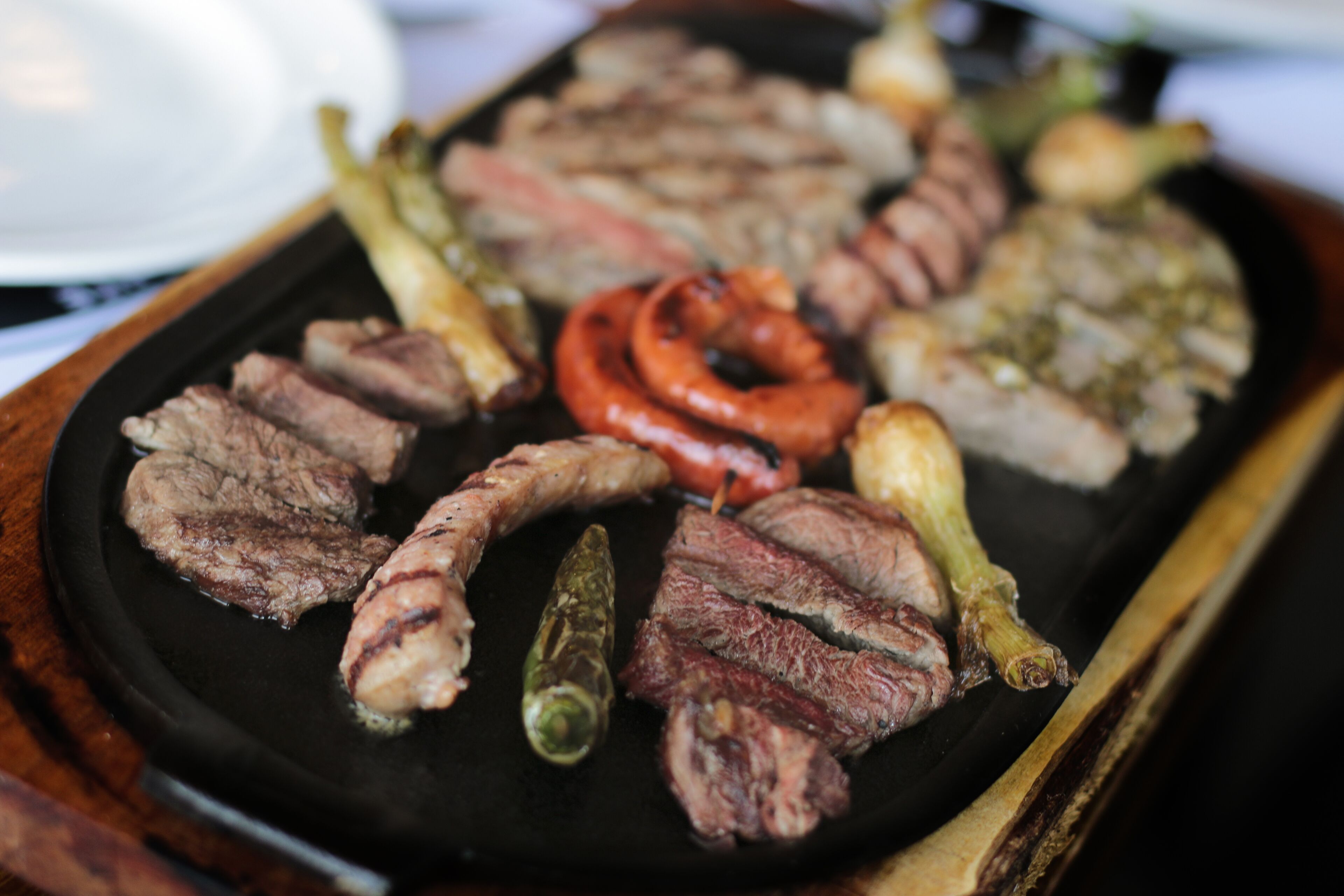 Une variété de viandes et de légumes grillés, présentés sur une assiette noire.