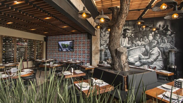A restaurant interior with wooden tables, chairs, and a large mural on the wall. - Hotel Rio Tequisquiapan (Tequisquiapan)