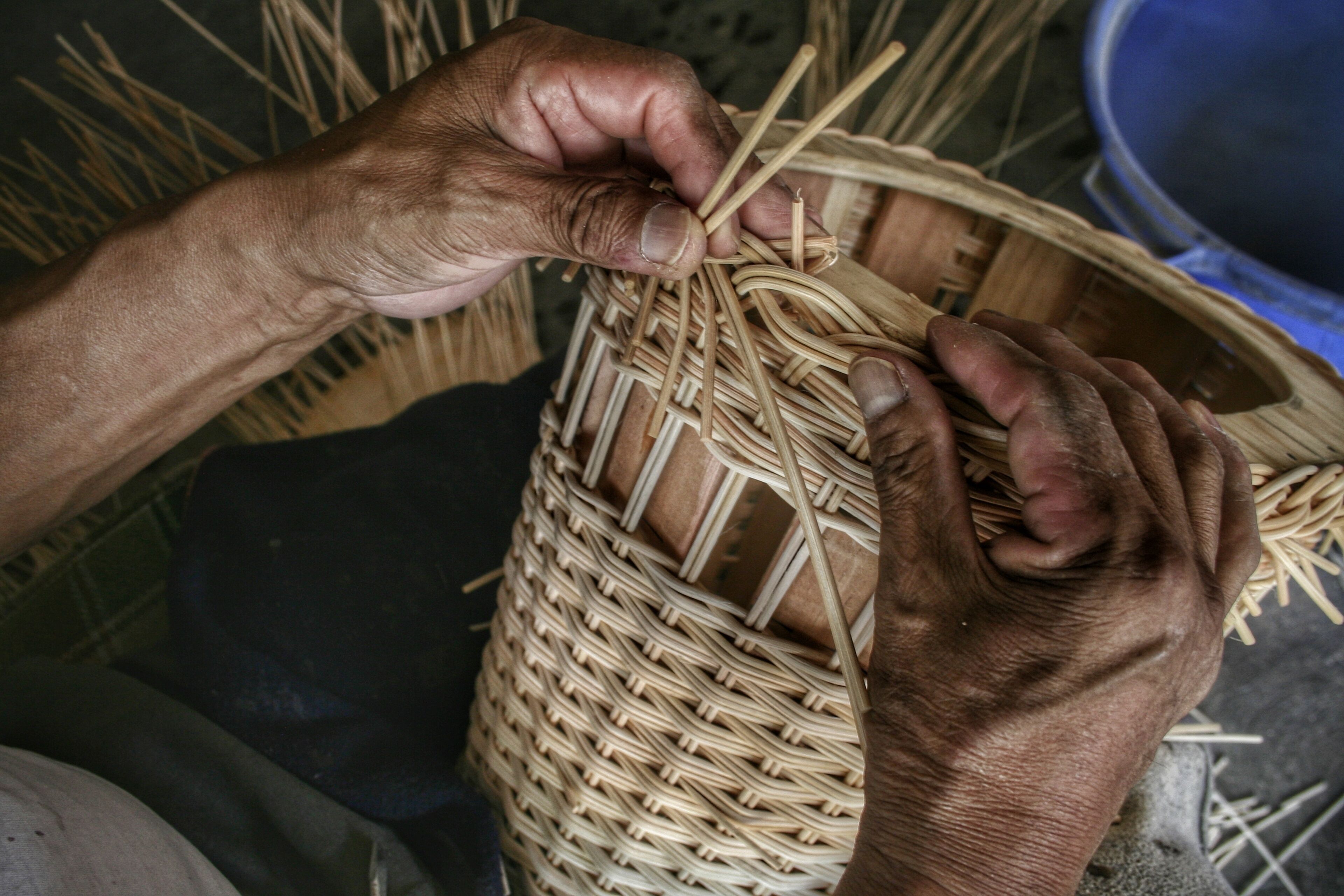 Hands weaving a basket.