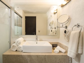 A bathroom with a large mirror, a sink, and a towel rack.