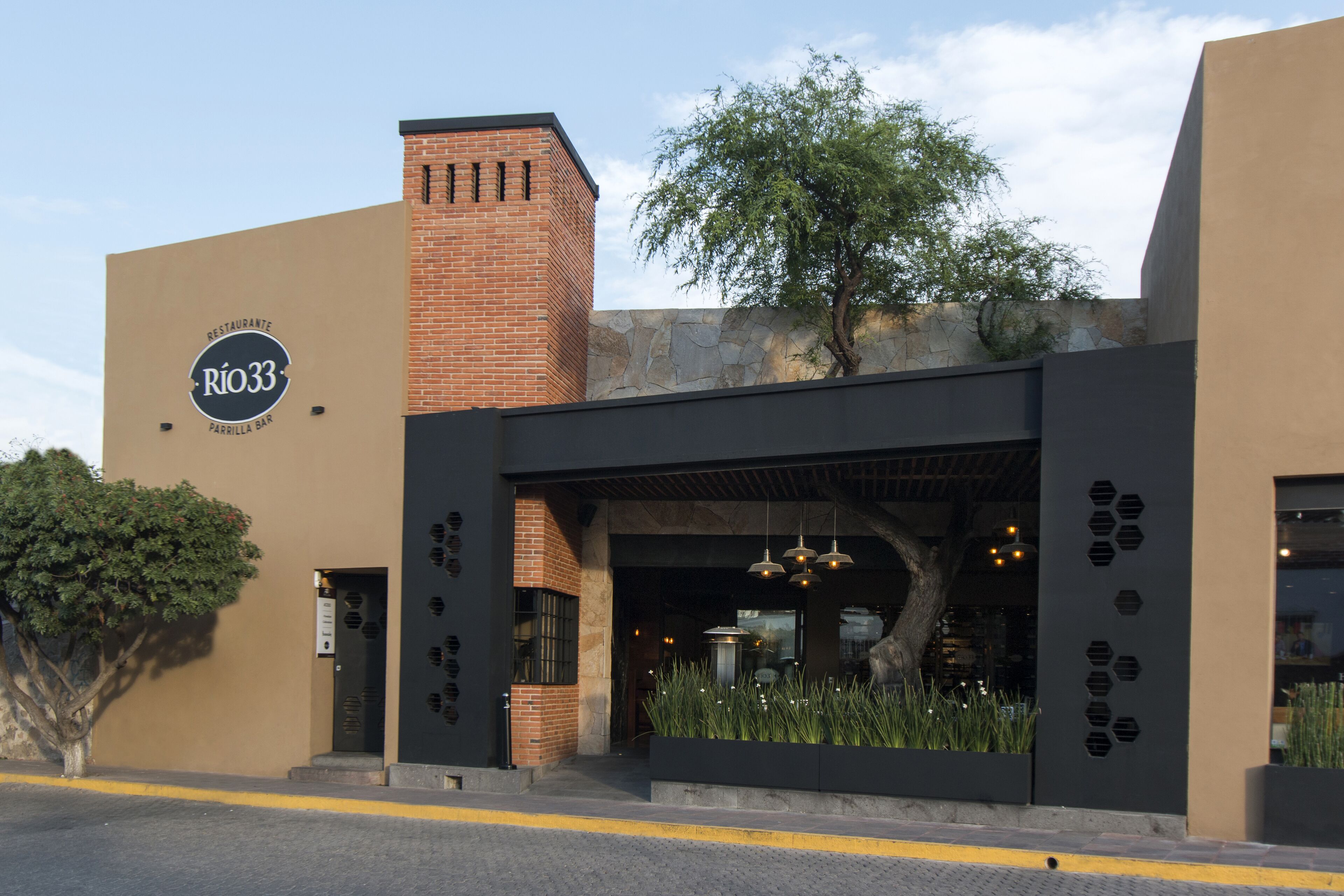 Un edificio con un cartel que dice "RIO33 PARRILLA BAR" y fachada de ladrillo.