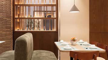 A dining area with a wooden table set for four, a cushioned bench, and a pendant light.