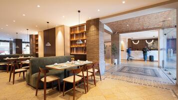 A modern restaurant with a brick wall, wooden furniture, and a tiled floor.