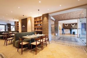 A modern restaurant with a brick wall, wooden furniture, and a tiled floor. - Hotel Bello Veracruz (Boca del Río)