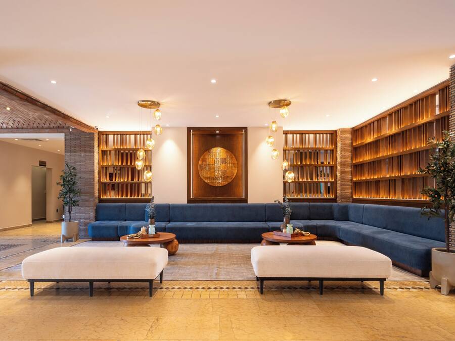 A modern lobby with a blue sofa, two ottomans, a coffee table, and a large wall art piece.