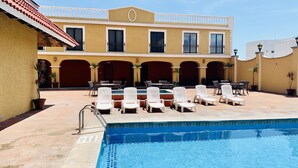 Un área junto a la piscina con sillones de descanso y una piscina.