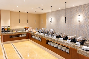 A buffet setup with multiple food stations, a marble-tiled floor, and pendant lighting. - Hotel Bello Veracruz (Boca del Río)