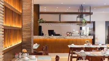 A modern restaurant interior with wooden paneling, a counter with a coffee machine, and tables set for dining.