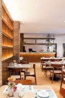 A modern restaurant interior with wooden paneling, a counter with a coffee machine, and tables set for dining.