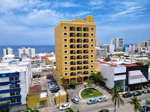 A high-rise hotel with multiple balconies, a parking lot, and a view of the ocean. - Hotel Bello Veracruz (Boca del Río)